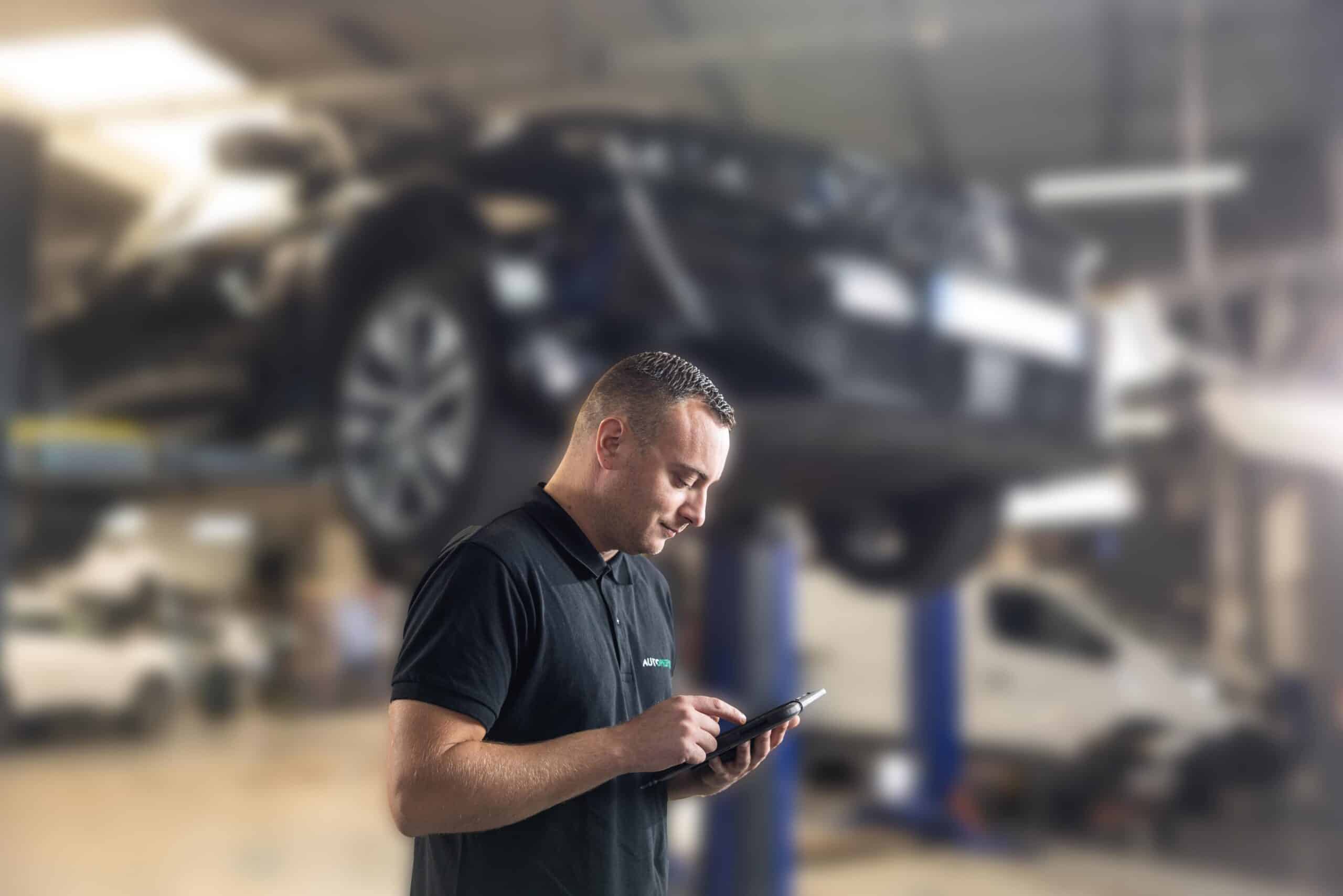 Un technicien utilise une tablette avec le logiciel de Progicar dans un garage